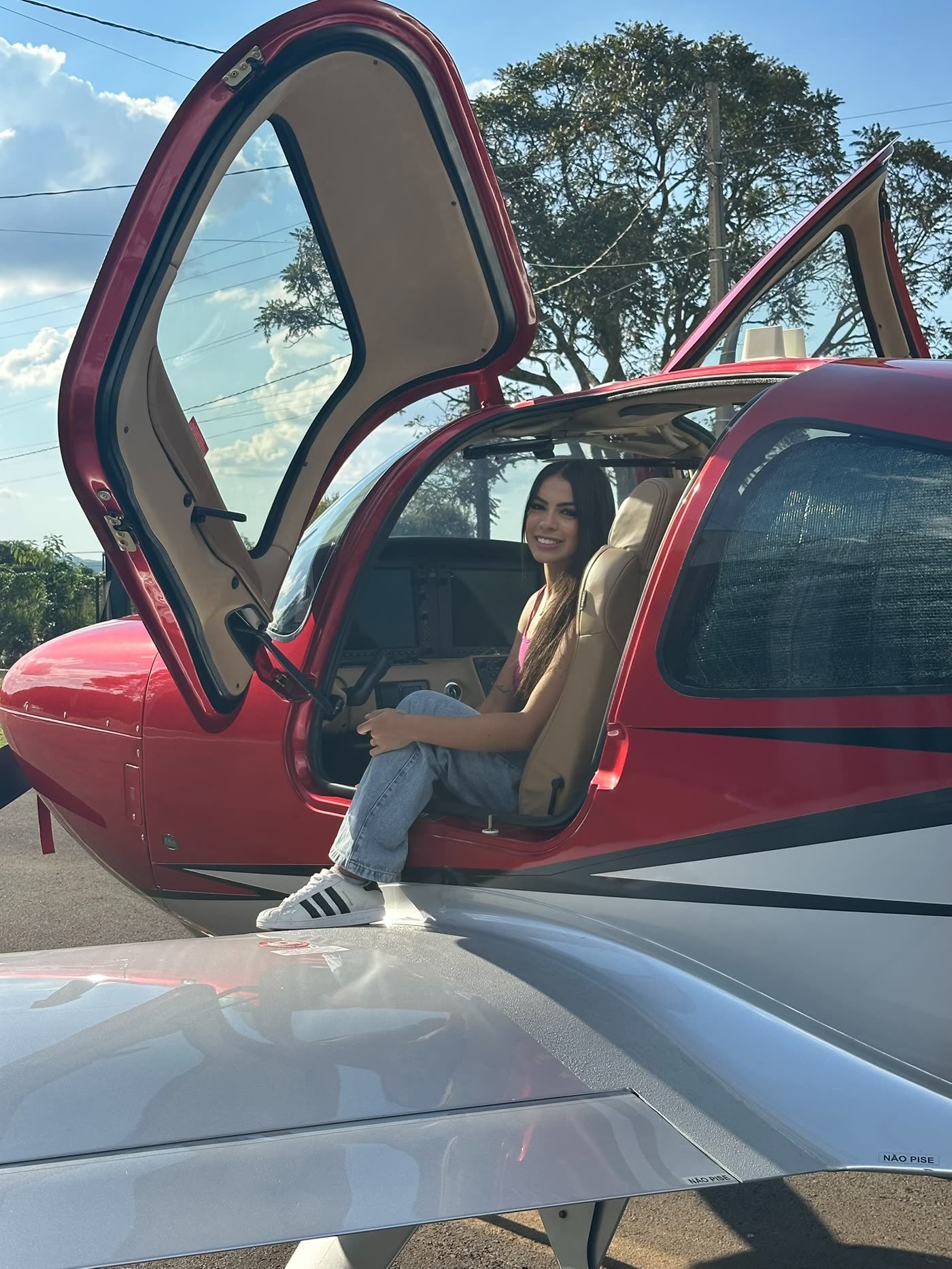 Micaely sentada na porta de um avião